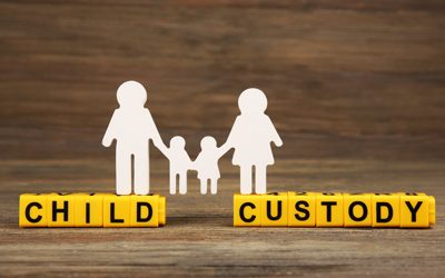 Paper cut out of a family standing on yellow block letters that spell child custody