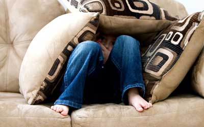 child hiding under pillows
